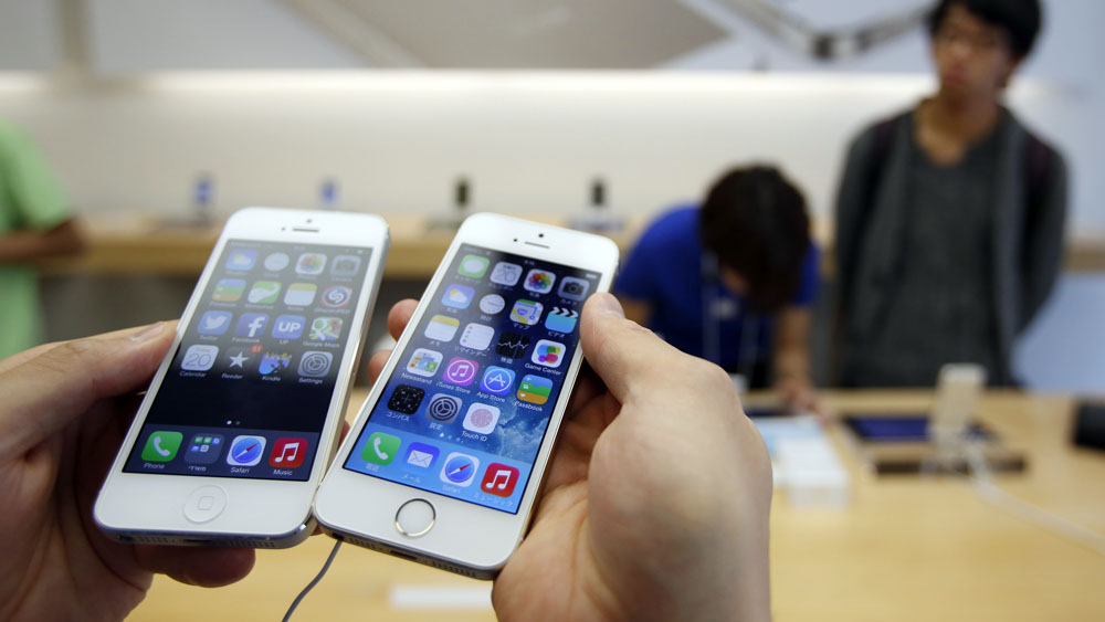 A man holds a new Apple iPhone 5S next to his iPhone 5 at an Apple Store at Tokyo's Ginza shopping district