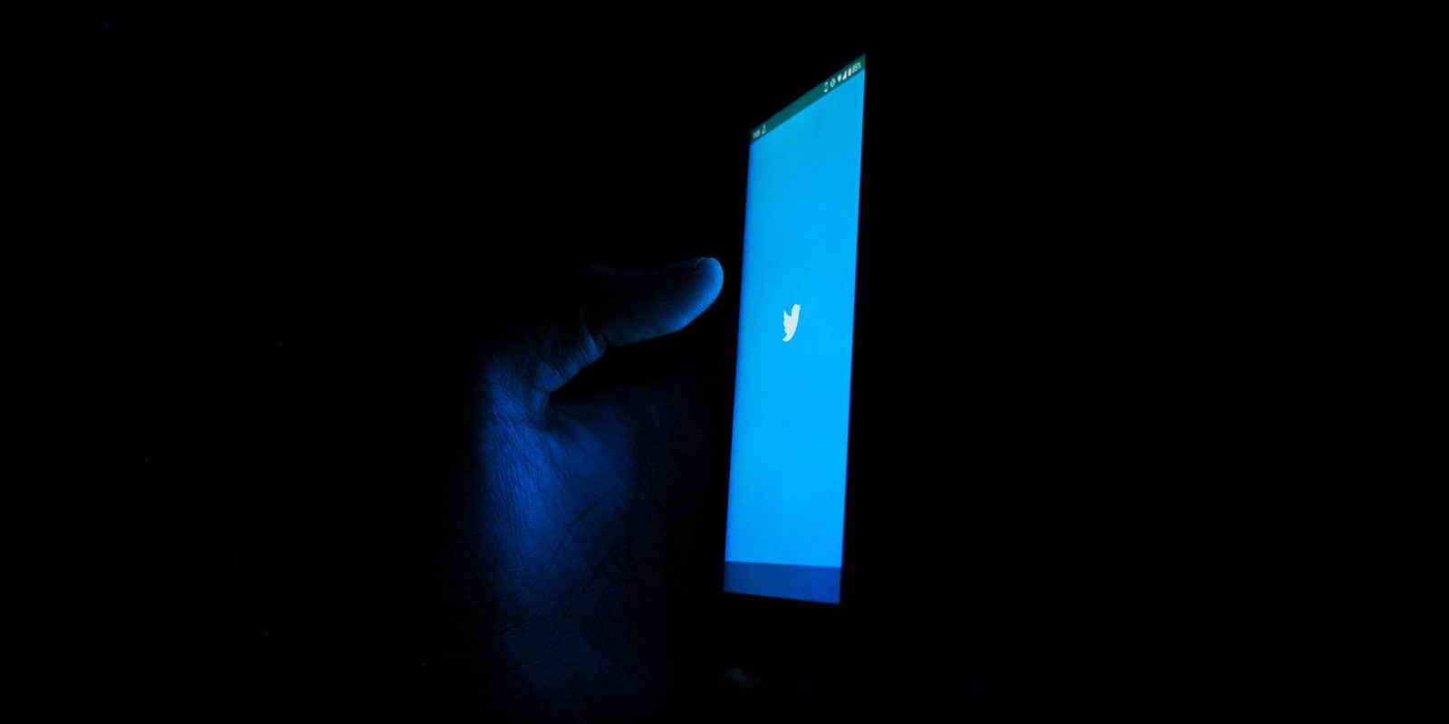 Twitter on smartphone in dark room | Reactions to Elon Musk buying Twitter