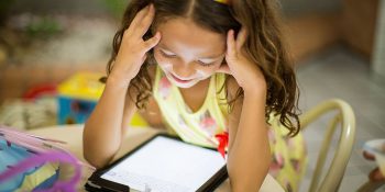 Young girl using an iPad | Bipartisan deal brings cheaper broadband to tens of millions of Americans