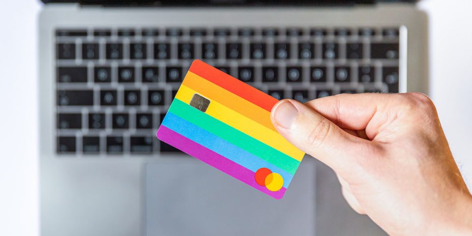 Chinese iPhone sales | Hand holding rainbow credit card above MacBook keyboard