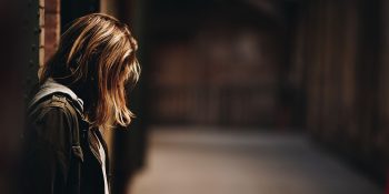 TikTok mental health | Girl in darkened corridor looking down