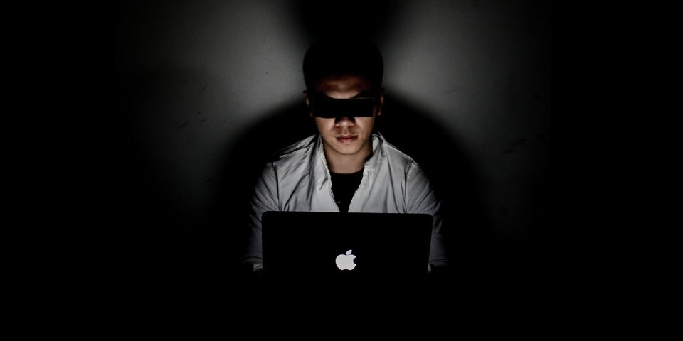 Chinese spy | Man in darkened room using MacBook
