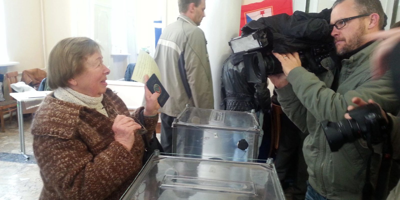 Sham referendums in Ukraine | Woman showing her passport to place ballot in transparent box
