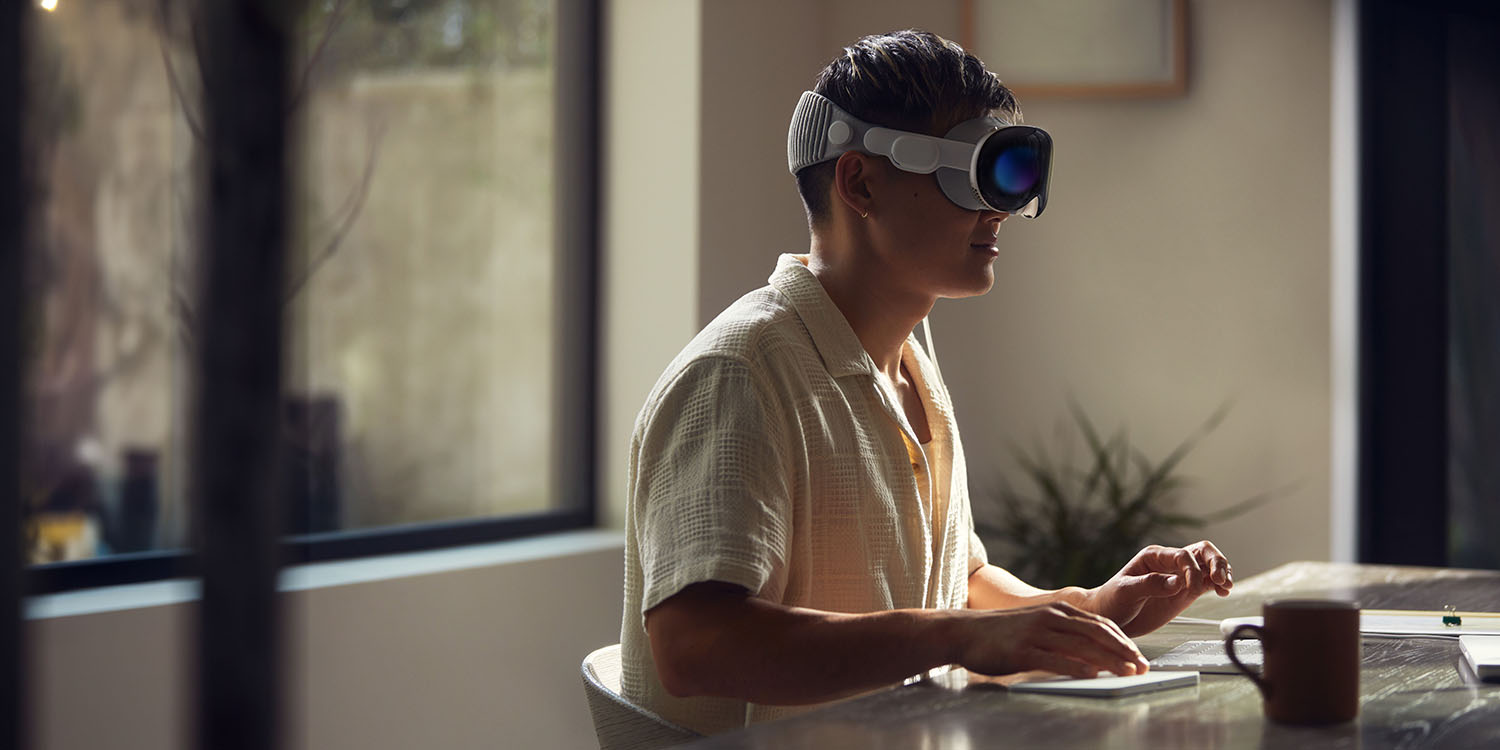 Mac Virtual Display | Man wearing Vision Pro in front of Mac