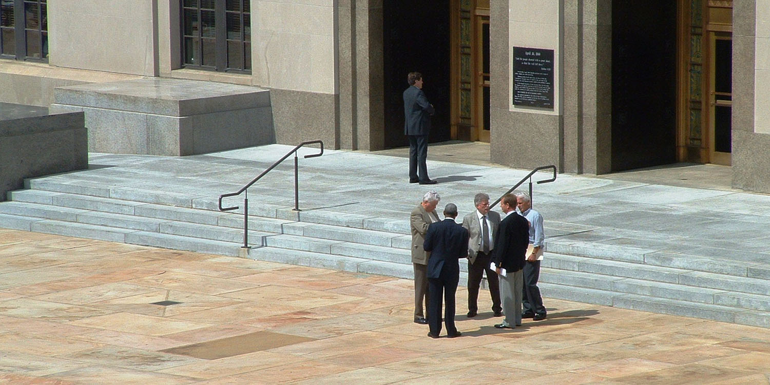 Qualcomm is harassing Apple | Stock photo of men on the steps of a building