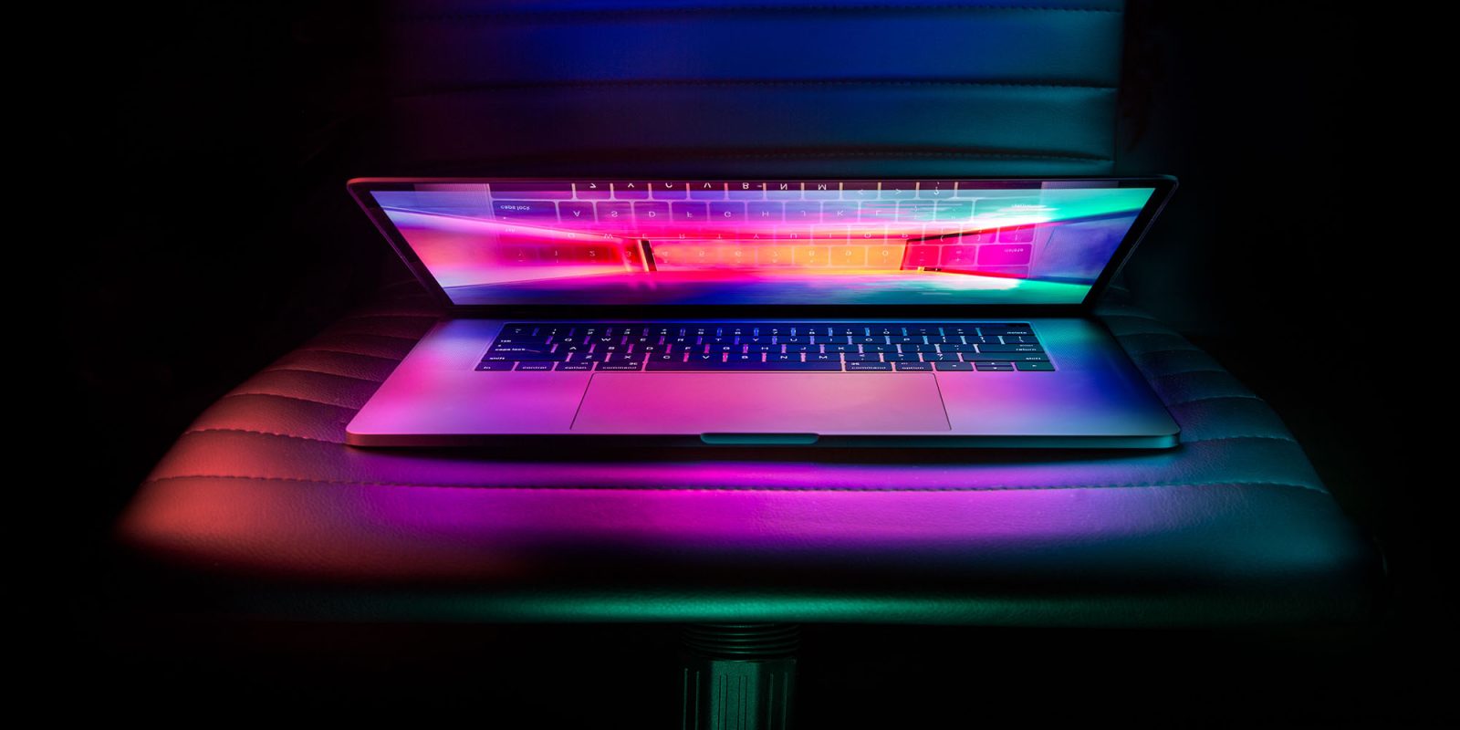 Mac shipments | MacBook with colored screen illuminating in in darkened room