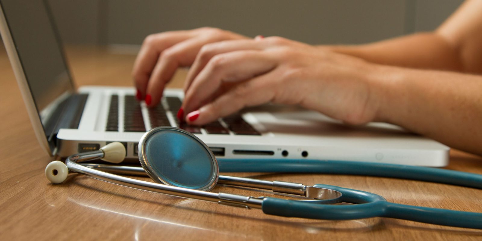 Doctors prescribing app, with walking steps targets | Typing on Mac next to stethoscope