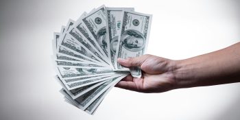 With three new upcoming launches, Apple products will push prices higher than ever | Hand holding out a bunch of $100 bills